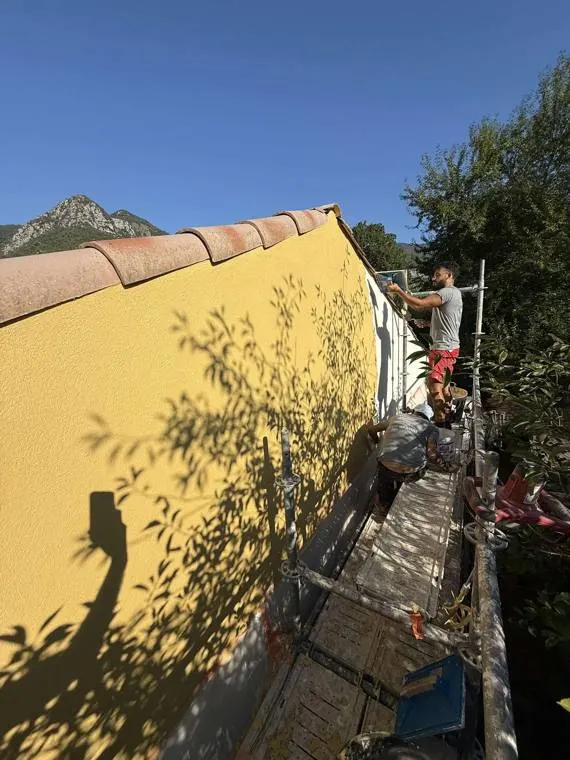 Équipe MVA Dynamics réalisant l'enduit d'une façade jaune