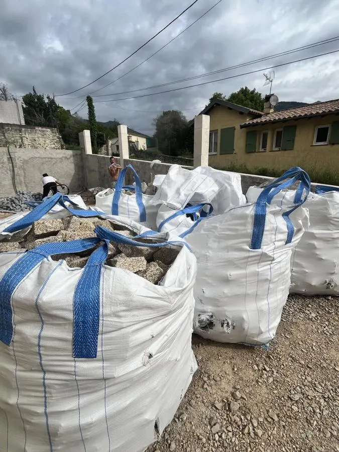 Big bags de matériaux devant un mur en cours de réalisation
