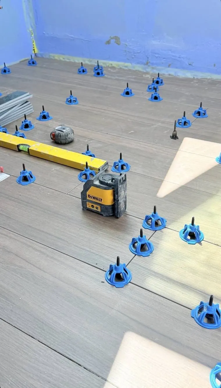 Pose de carrelage dans une salle d'eau : sol en cours de pose, niveau et laser, murs protégés