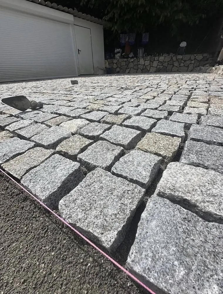 Pavés portugais en granit en cours de pose devant un garage