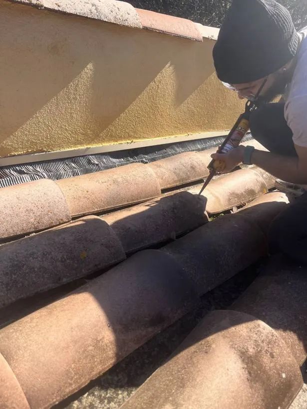 Ouvrier appliquant un mastic sur des tuiles